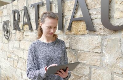 Frau mit Tablet vor dem Rathaus