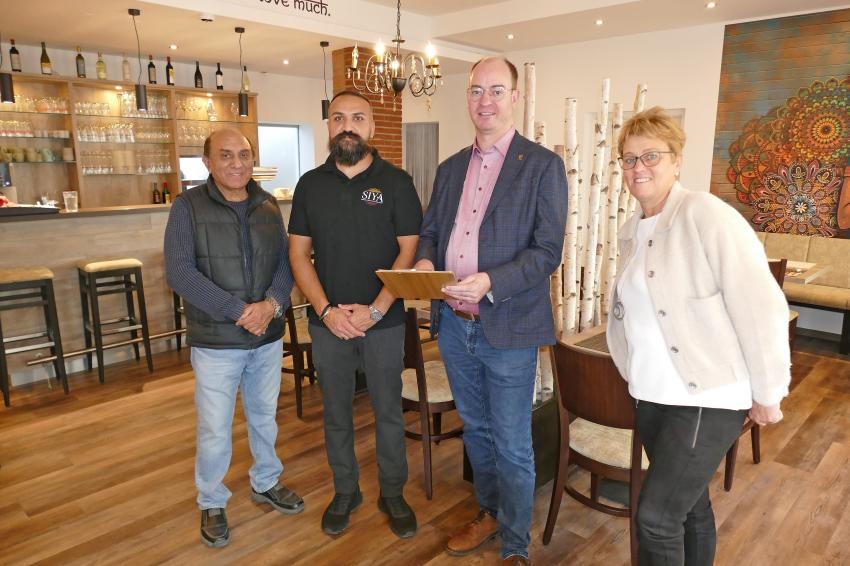 Vier Personen stellen sich für einGruppenbild im geschlossenen Raum auf